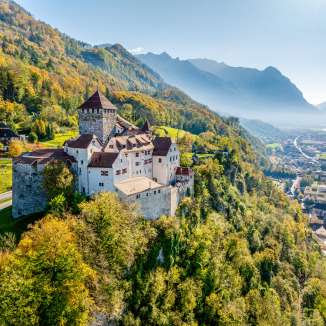 Il castello di Vaduz in Liechtenstein nell'autunno dorato, con vista sulla valle alpina del Reno e sulla città di Vaduz