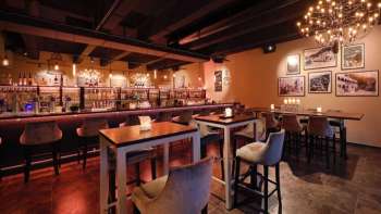 Interni eleganti del ristorante con elementi in legno scuro, area bar e sedie confortevoli in un ambiente accogliente.