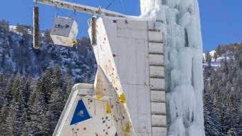 Torre di ghiaccio ghiacciata a Malbun con vie di arrampicata e punti di sosta visibili, in un cielo azzurro