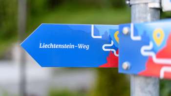 Cartello blu con la scritta «Sentiero del Liechtenstein» in un design moderno.