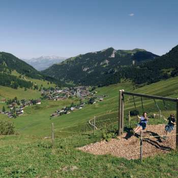 Una famiglia si diverte a dondolare insieme sul sentiero delle altalene a Malbun