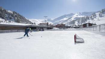 Ampia pista di pattinaggio a Malbun con un impressionante sfondo montano sotto un sole splendente