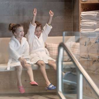 Due bambini in accappatoio si godono l'area benessere dell'Hotel Gorfion - vacanze in famiglia all'insegna del benessere a Malbun.