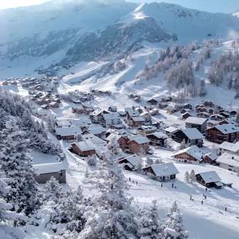 Case innevate e piste da sci nel villaggio alpino invernale di Malbun, immerso in un paesaggio montano da sogno.