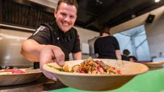 Lo chef serve un piatto di piatti regionali al Genussfestival di Vaduz, nel Liechtenstein - evento culinario incentrato sul divertimento