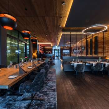 Elegante sala da pranzo con elementi di illuminazione moderni e rivestimenti in legno alle pareti.