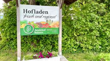 L'insegna dell'agriturismo Aeulehof con la scritta "Fresco e regionale" davanti a una siepe verde a Triesen.