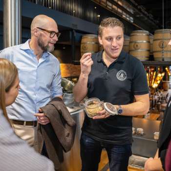Un dipendente spiega gli ingredienti della produzione di birra a un gruppo di ospiti interessati durante una visita al birrificio.