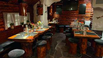 Vista di un ristorante rustico con mobili in legno, tavoli decorati in verde e candele.