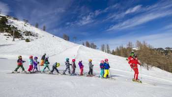 Il maestro di sci dell'Area giochi Malbi Park Malbun motiva i bambini sulla pista di pratica - l'ambiente perfetto per le loro prime curve sulla neve
