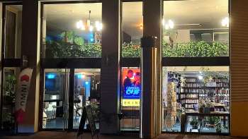 Vista esterna illuminata del cinema Skino di Schaan di notte, con grandi vetrate e un'atmosfera invitante.