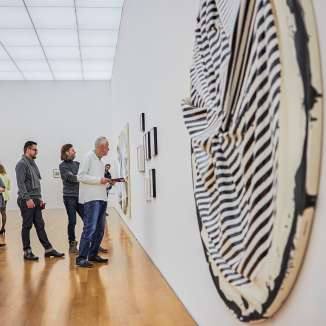 I visitatori ammirano le opere d'arte moderna in una galleria del museo d’arte del Liechtenstein con architettura chiara e pavimento in legno