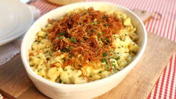 Käsknöpfle (gnocchetti al formaggio) con cipolle fritte - serviti in un piatto su una tavola di legno