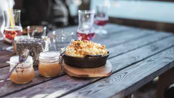 Specialità regionaleKäsknöpflecon salsa di mele su un tavolo di legno davanti a uno sfondo alpino