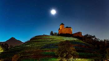 La Rocca di Gutenberg illuminata di notte, con la luna piena, immersa nei vigneti