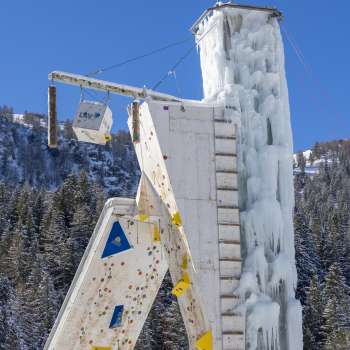 Torre di ghiaccio ghiacciata a Malbun con vie di arrampicata e punti di sosta visibili, in un cielo azzurro