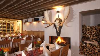 Ambiente accogliente del ristorante con travi di legno rustiche e camino