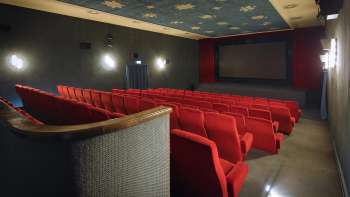 Vista laterale della sala cinematografica dell'Altes Kino Vaduz con poltrone rosse e illuminazione d'atmosfera.