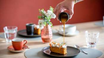 Il dessert è sormontato da salsa al caramello, tazze da caffè e decorazioni da tavola in stile sullo sfondo