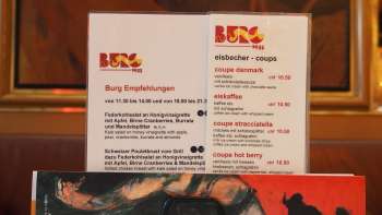 Il menu della Brasserie Burg davanti a un murale colorato: delizie culinarie e arte nel cuore di Vaduz.