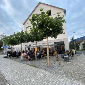 Vivace terrazza del St. Martins Pub am Platz , con alberi ombrosi e ospiti ai tavoli.