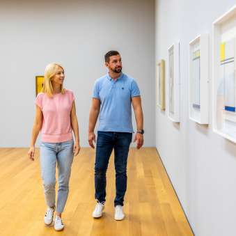 Una coppia passeggia nel museo d’arte del Liechtenstein a Vaduz e osserva le opere d'arte contemporanea appese alle pareti.