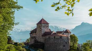 Vista pittoresca del castello di Vaduz, immerso nel verde di colline e foreste.