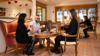 Tre persone nel Keramikcafé in Liechtenstein con caffè e tè in un'accogliente atmosfera lounge.