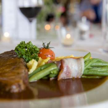 Primo piano di un piatto principale con verdure verdi, pancetta e salsa cremosa sul piatto