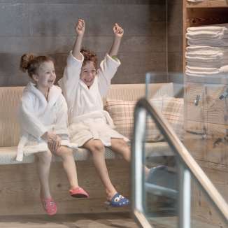 Due bambini in accappatoio si godono l'area benessere dell'Hotel Gorfion - vacanze in famiglia all'insegna del benessere a Malbun.