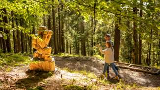 Due visitatori scoprono una figura di legno intagliata lungo il «sentiero delle leggende Walser» a Triesenberg, in Liechtenstein - un sentiero escursionistico a tema mistico nella foresta
