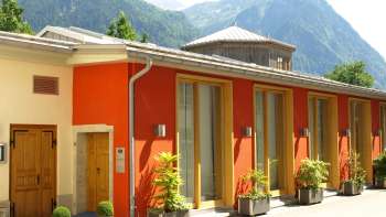 Vista esterna del Centro culturale Gasometro con la facciata colorata e il panorama alpino sullo sfondo.