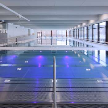 Moderna piscina coperta a Triesen con vasca illuminata e ampia vetrata.