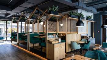 Ristorante moderno con elegante struttura in legno, sedute imbottite di colore verde e disposizione dei locali creativa