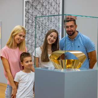 Una famiglia osserva una scultura d'oro nel Museo d’arte del Liechtenstein - arte per grandi e piccini nel cuore di Vaduz.