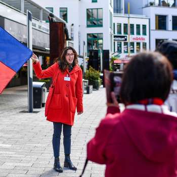 Una guida cittadina con la bandiera del Liechtenstein accoglie un gruppo di turisti a Vaduz