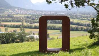 Scultura "Resonare" in metallo arrugginito sulla collina del Krest con vista sulla valle del Reno e sulle montagne sullo sfondo. Scultura "Resonare" in metallo arrugginito sulla collina del Krest con vista sulla valle del Reno e sulle montagne sullo sfondo.