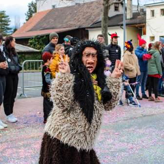 Strega di Schaan mascherata alla sfilata di carnevale di Schaan, Liechtenstein, davanti a un pubblico e a coriandoli colorati sulla strada