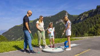  Una famiglia che gioca a minigolf tra le montagne di Malbun sotto un sole splendente