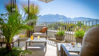 Terrazza soleggiata con moderni mobili da salotto e panorama alpino sullo sfondo