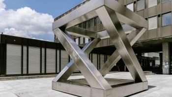 Scultura geometrica Z-Cube di Georg Malin a Vaduz - superfici sfalsate in acciaio inossidabile a forma di cubo in una piazza pubblica.