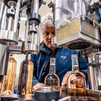 Un dipendente controlla il riempimento a macchina delle bottiglie di vino in un'azienda vinicola del Liechtenstein