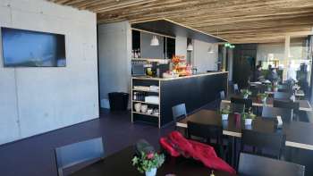 Sala da pranzo moderna con tavoli scuri, composizioni di fiori freschi e un tetto rustico in legno