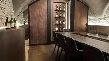 Elegante sala degustazione dell'WY Weinbar con soffitto a volta ed elegante tavolo in legno per esclusive degustazioni di vino.
