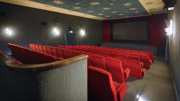 Vista laterale della sala cinematografica dell'Altes Kino Vaduz con poltrone rosse e illuminazione d'atmosfera.