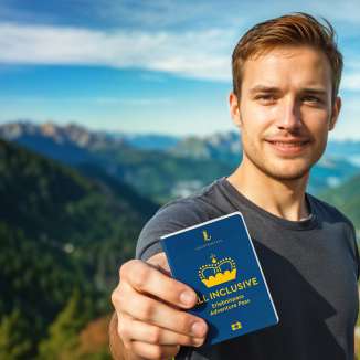 Uomo mostra il «Pass attrazioni TUTTO INCLUSO» con panorama montano sullo sfondo