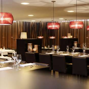 Sala da pranzo elegante con mobili scuri, lampade rosse di design e un ambiente elegante