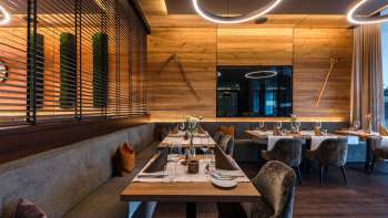 Moderna area ristorante con arredi in legno pregiato, tavoli eleganti e comode poltrone.