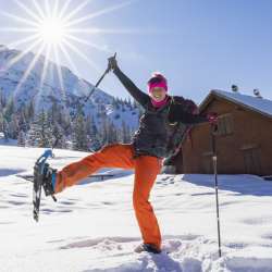 Un'allegra ciaspolatrice si gode l'inverno a Malbun, nel Liechtenstein, sotto un sole radioso.