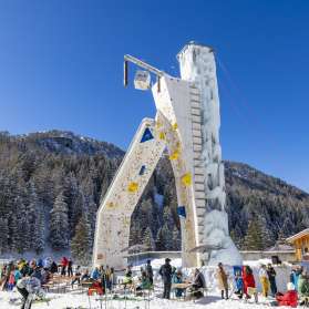 La torre di arrampicata ghiacciata di Malbun, circondata da ospiti invernali sullo sfondo alpino: un'attrazione per gli appassionati di sport invernali nel Liechtenstein.